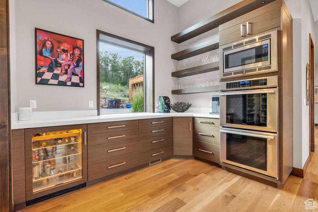 Kitchen with wine cooler, stainless steel appliances, and light wood-type flooring