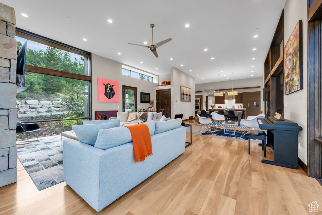 Living room featuring light hardwood / wood-style flooring, ceiling fan, and a high ceiling