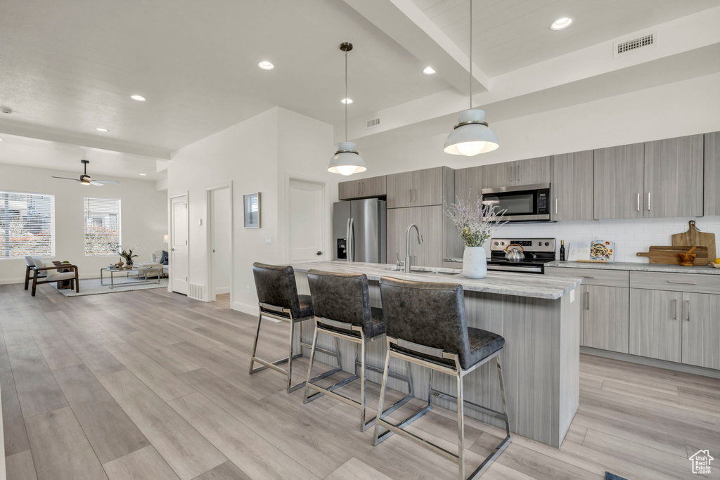 Kitchen featuring appliances with stainless steel finishes, pendant lighting, a breakfast bar, and ceiling fan