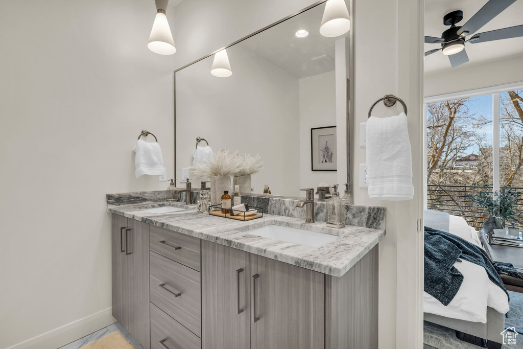 Bathroom featuring double sink, vanity with extensive cabinet space, and ceiling fan