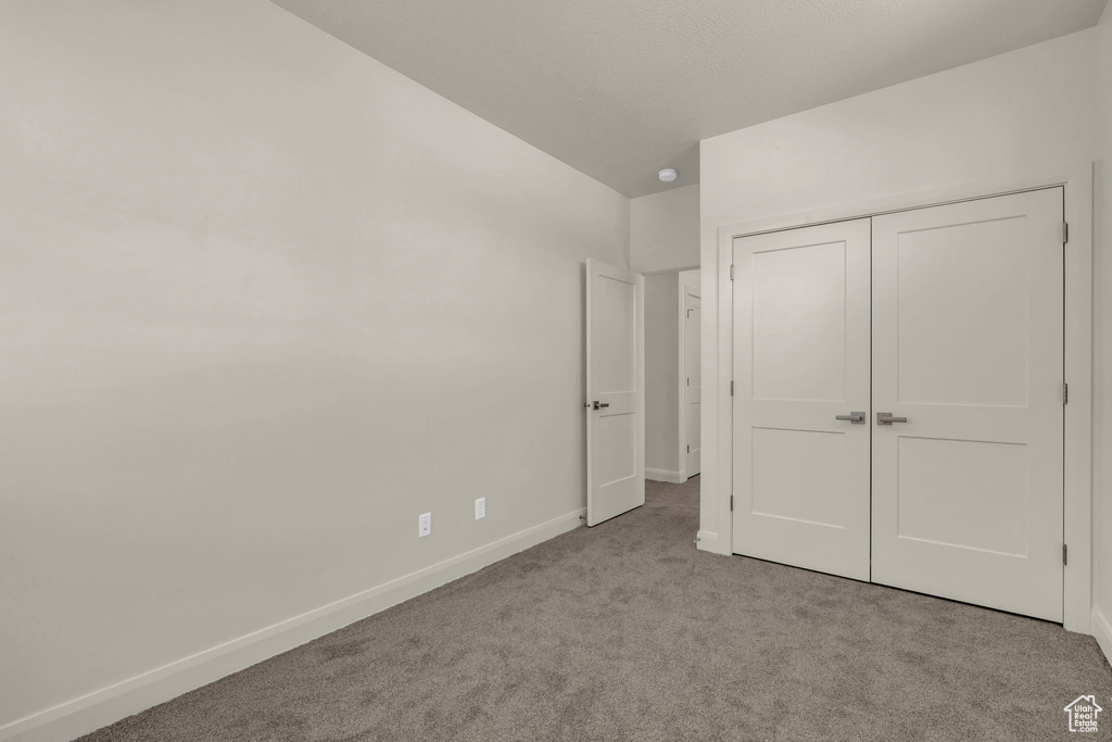 Unfurnished bedroom with light carpet and a closet