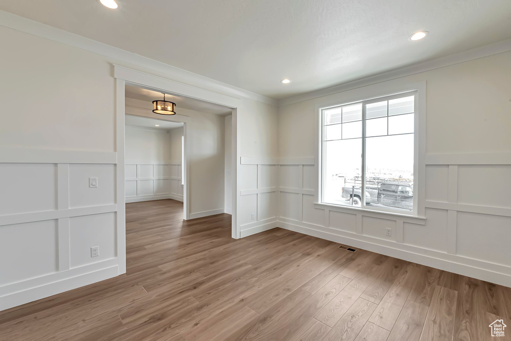Empty room featuring light hardwood / wood-style flooring and ornamental molding