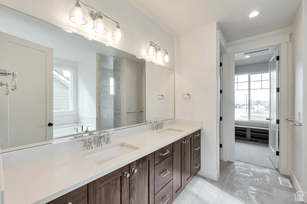 Bathroom featuring a bath, double sink vanity, and tile floors
