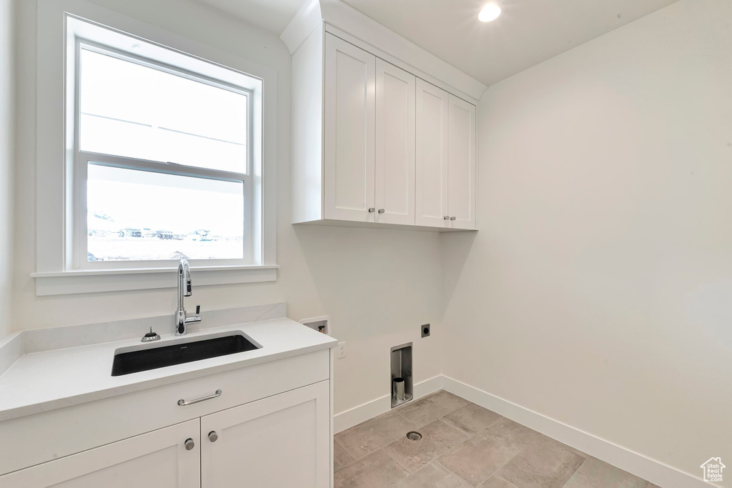 Washroom with sink, cabinets, light tile floors, and hookup for an electric dryer