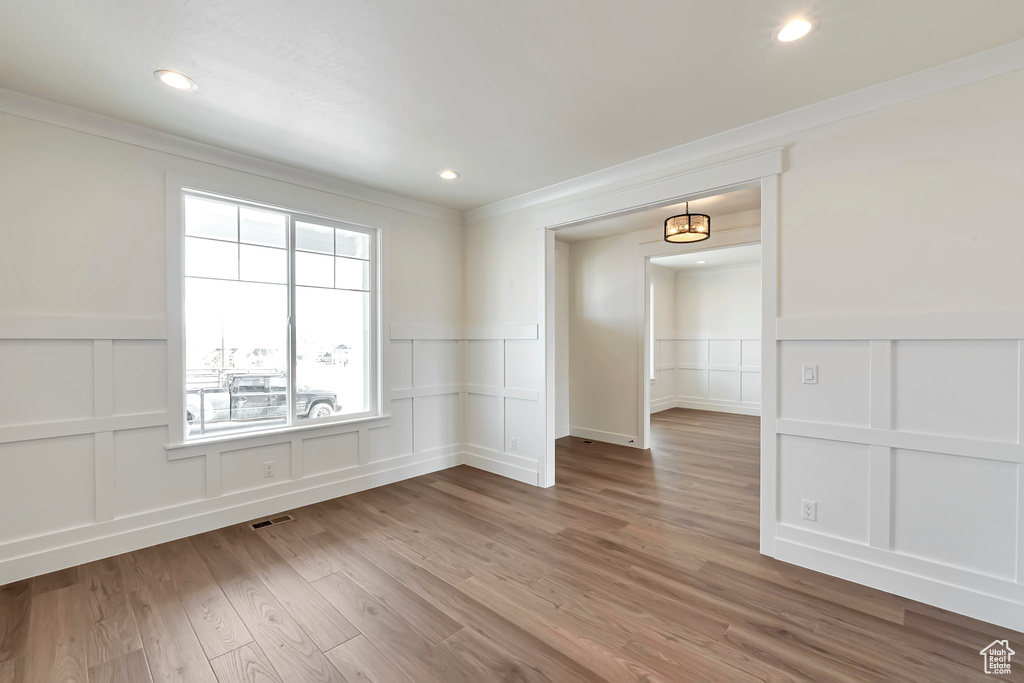 Empty room with ornamental molding and hardwood / wood-style floors
