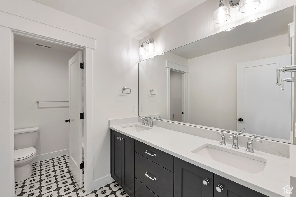 Bathroom featuring double vanity, toilet, and tile floors