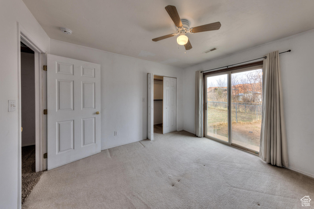 Unfurnished bedroom with access to outside, a closet, light colored carpet, and ceiling fan