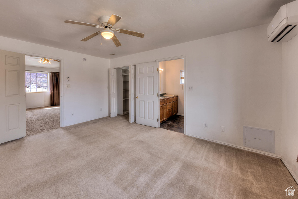 Unfurnished bedroom with connected bathroom, ceiling fan, a closet, carpet flooring, and a wall mounted AC