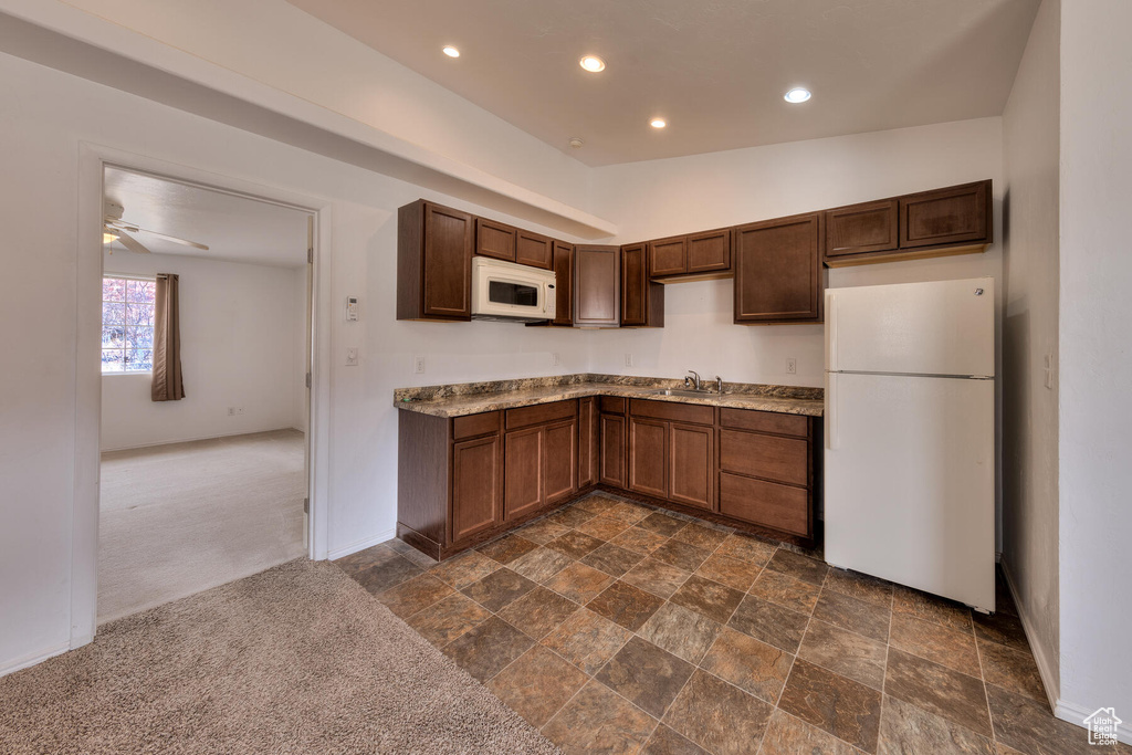 Kitchen featuring sink, white appliances, lofted ceiling, dark colored carpet, and ceiling fan