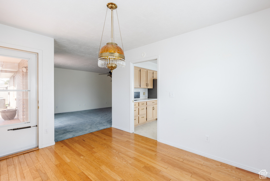 Unfurnished room featuring a chandelier and light hardwood / wood-style floors
