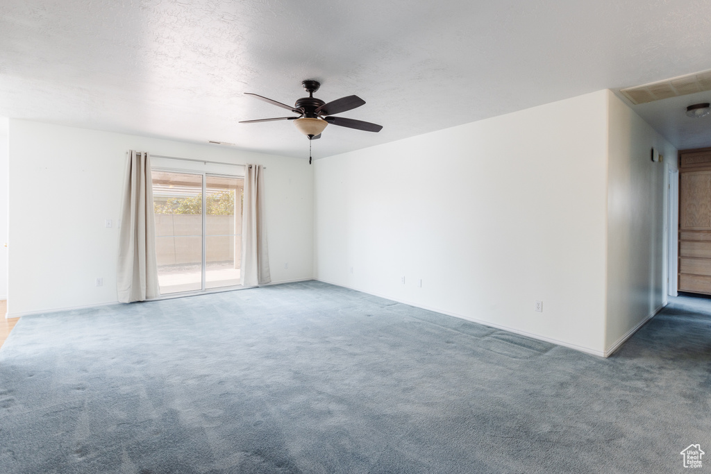 Empty room with dark carpet and ceiling fan