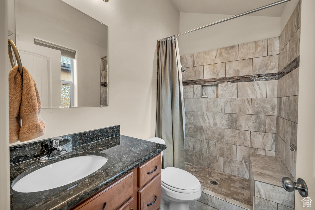 Bathroom featuring a shower with curtain, tile floors, vanity, and toilet