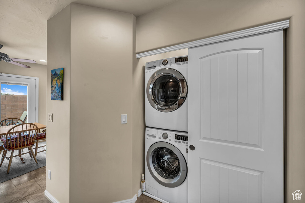 Laundry room featuring ceiling fan, stacked washer / drying machine, and light tile flooring
