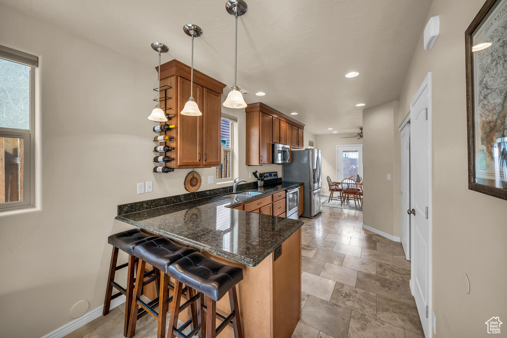 Kitchen featuring ceiling fan, kitchen peninsula, stainless steel appliances, decorative light fixtures, and light tile floors