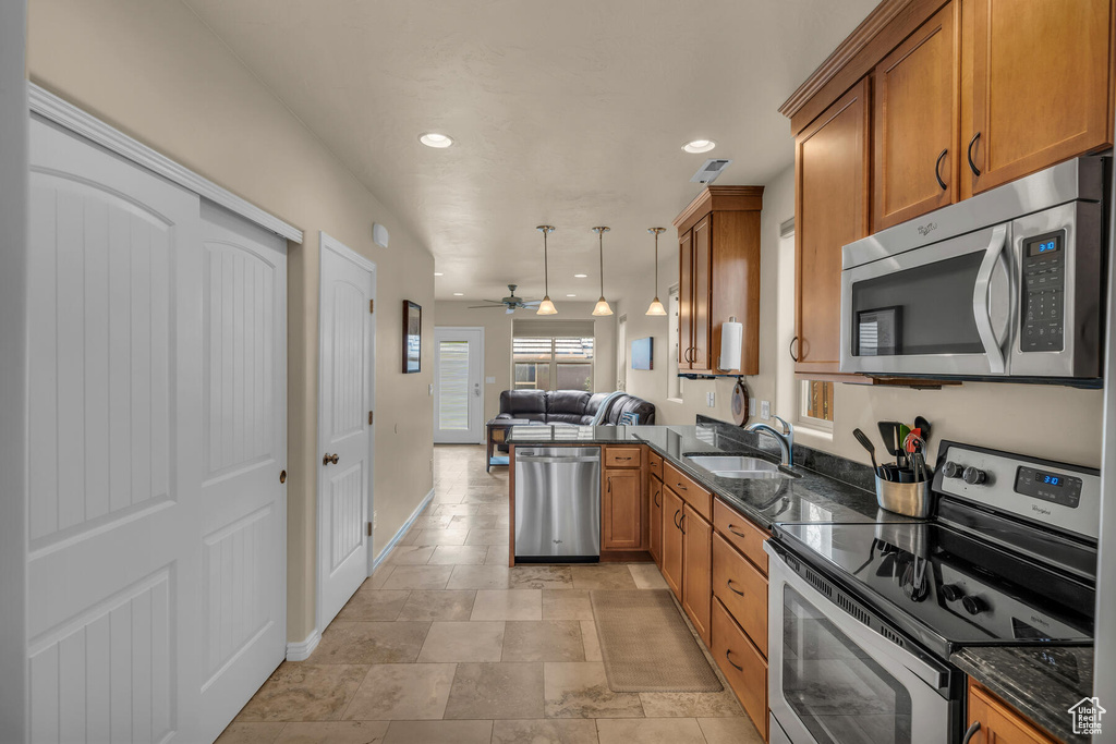 Kitchen featuring ceiling fan, stainless steel appliances, light tile floors, sink, and hanging light fixtures