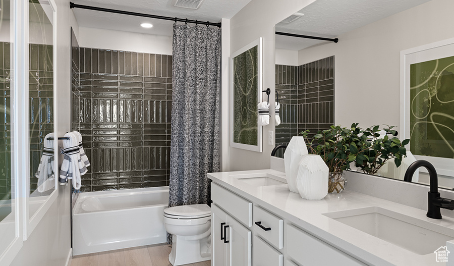 Full bathroom featuring shower / tub combo, dual vanity, hardwood / wood-style floors, and toilet
