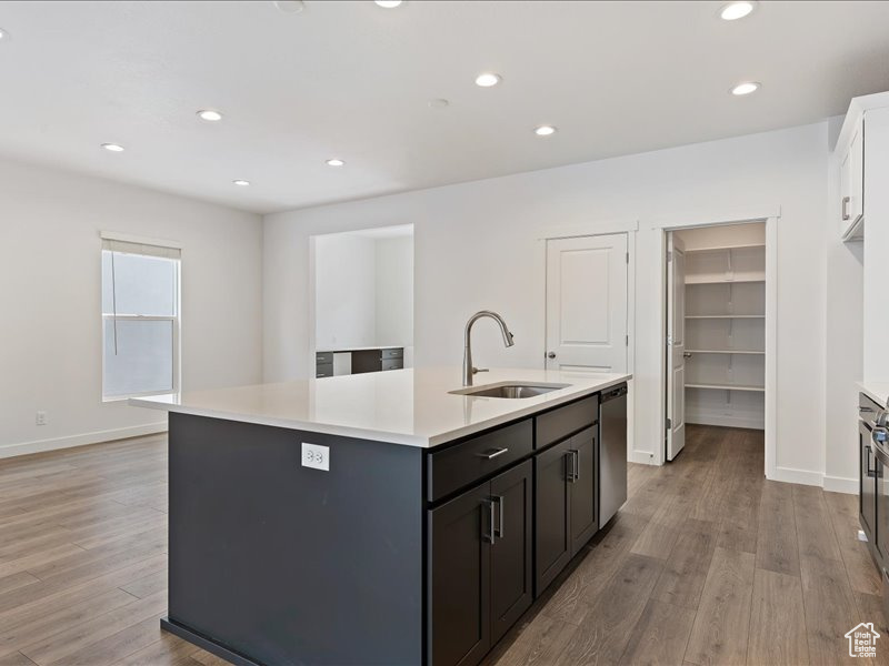 Kitchen featuring sink, light hardwood / wood-style flooring, white cabinetry, and a kitchen island with sink