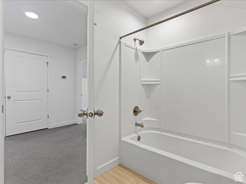 Bathroom with wood-type flooring and tub / shower combination