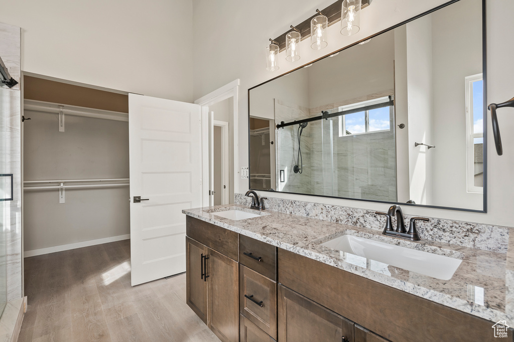 Bathroom with a shower with shower door, double sink vanity, and wood-type flooring