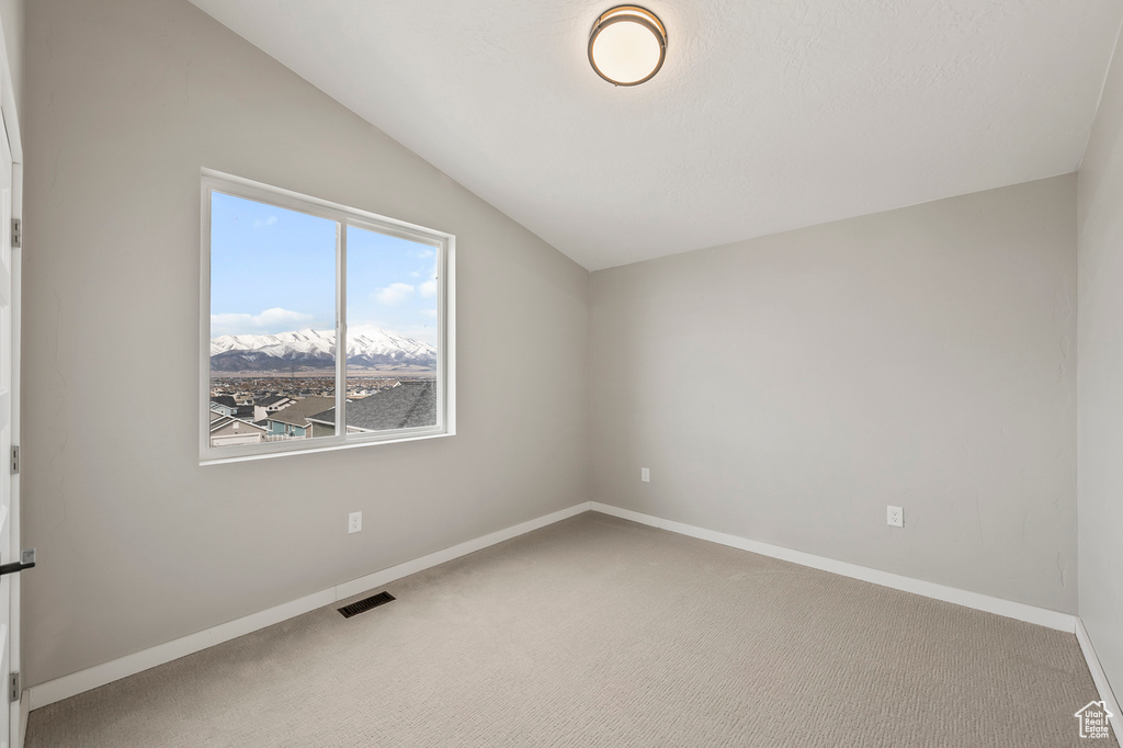 Empty room featuring vaulted ceiling and light colored carpet