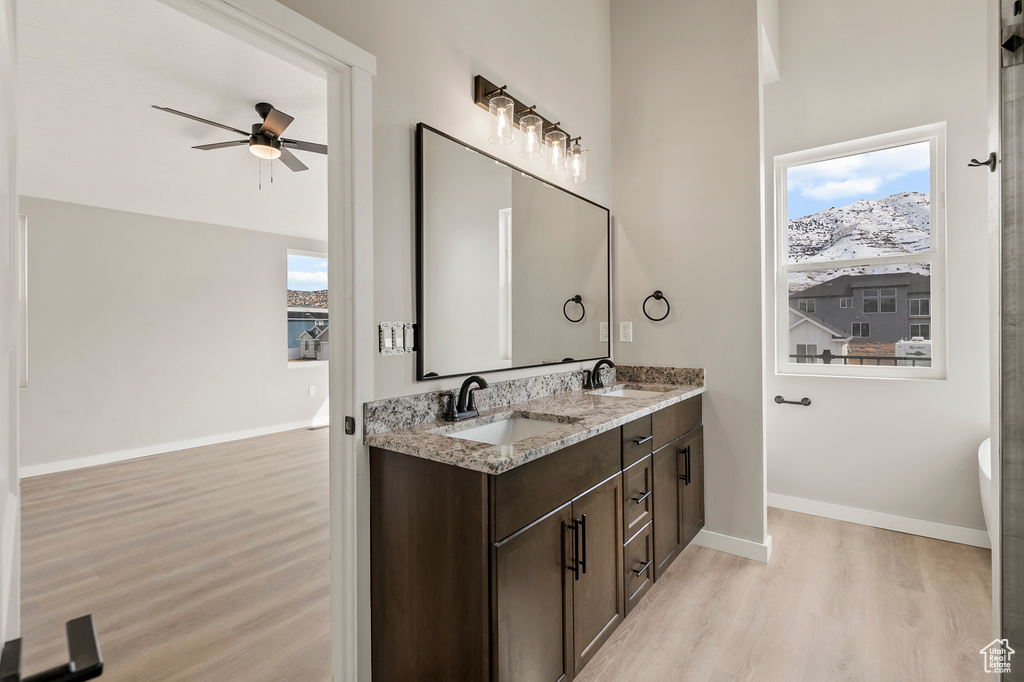 Bathroom featuring hardwood / wood-style floors, ceiling fan, and dual bowl vanity
