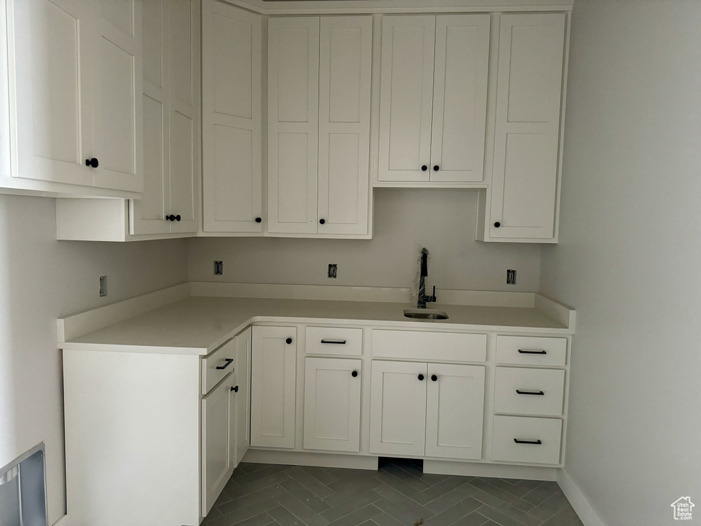 Kitchen featuring white cabinets, dark tile flooring, and sink