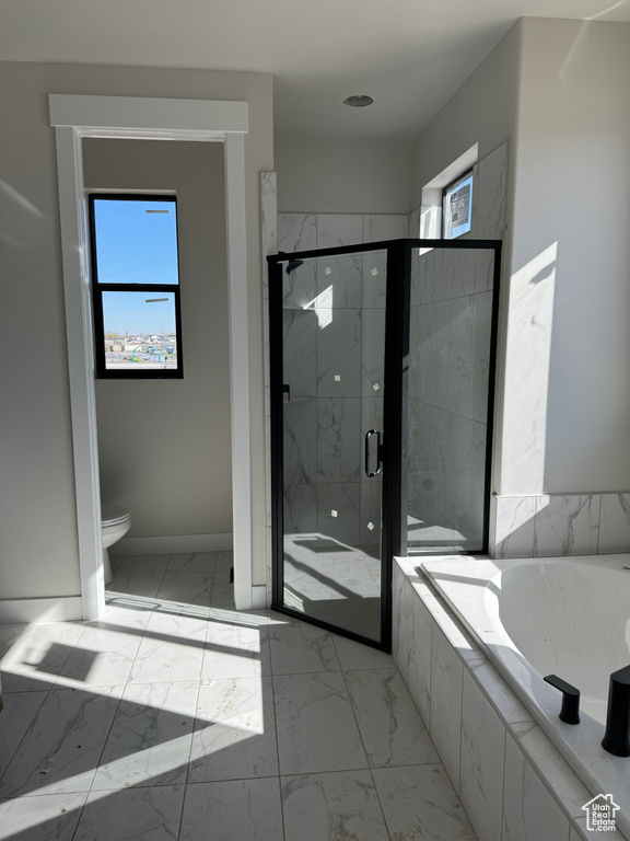 Bathroom featuring plenty of natural light, shower with separate bathtub, tile floors, and toilet