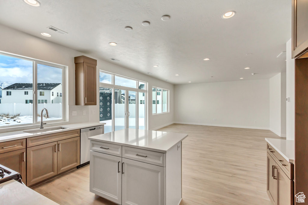 Kitchen featuring a kitchen island, sink, dishwasher, and light wood-type flooring