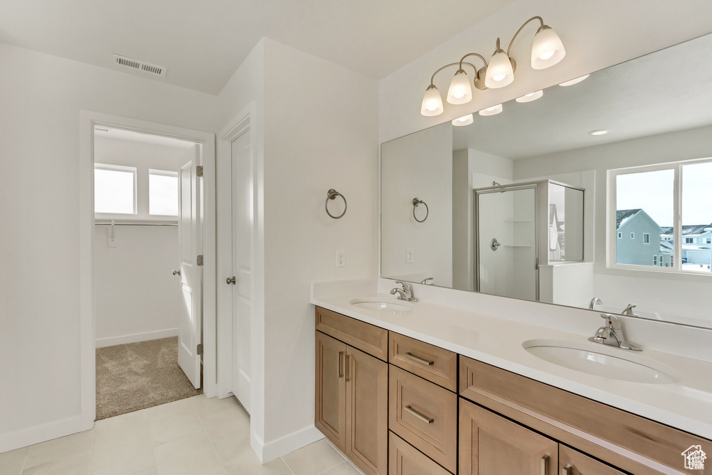 Bathroom with a wealth of natural light, dual sinks, vanity with extensive cabinet space, and tile floors