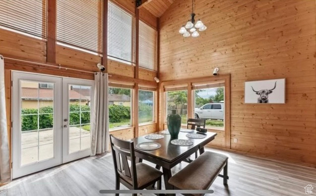 Dining area featuring a wealth of natural light, wood walls, light hardwood / wood-style floors, and high vaulted ceiling
