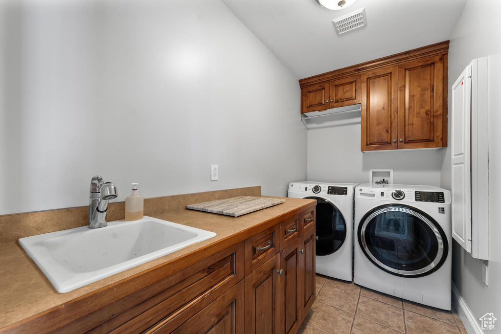Washroom with independent washer and dryer, cabinets, light tile flooring, sink, and hookup for a washing machine