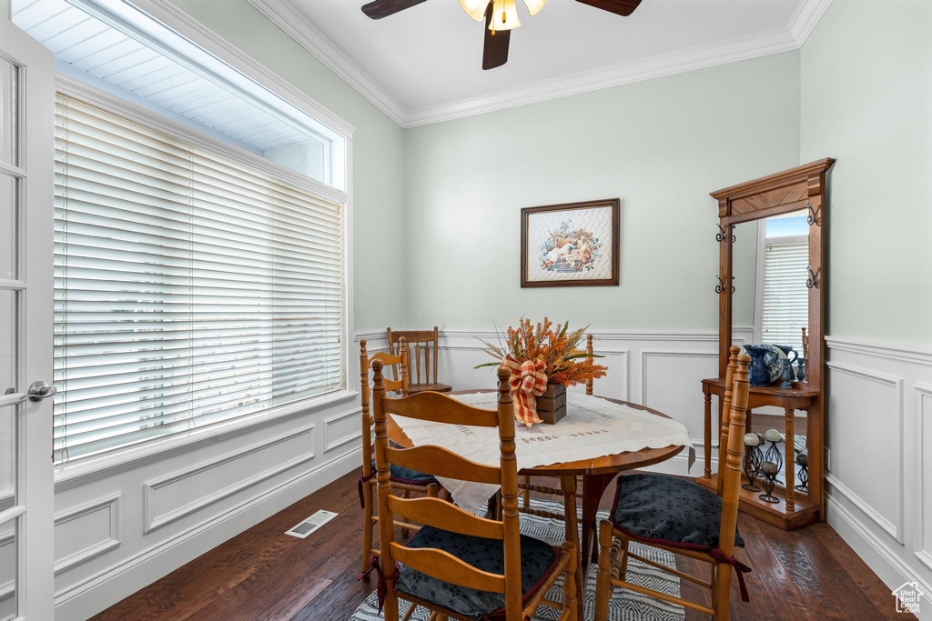 Dining room with ornamental molding, dark hardwood / wood-style flooring, and ceiling fan