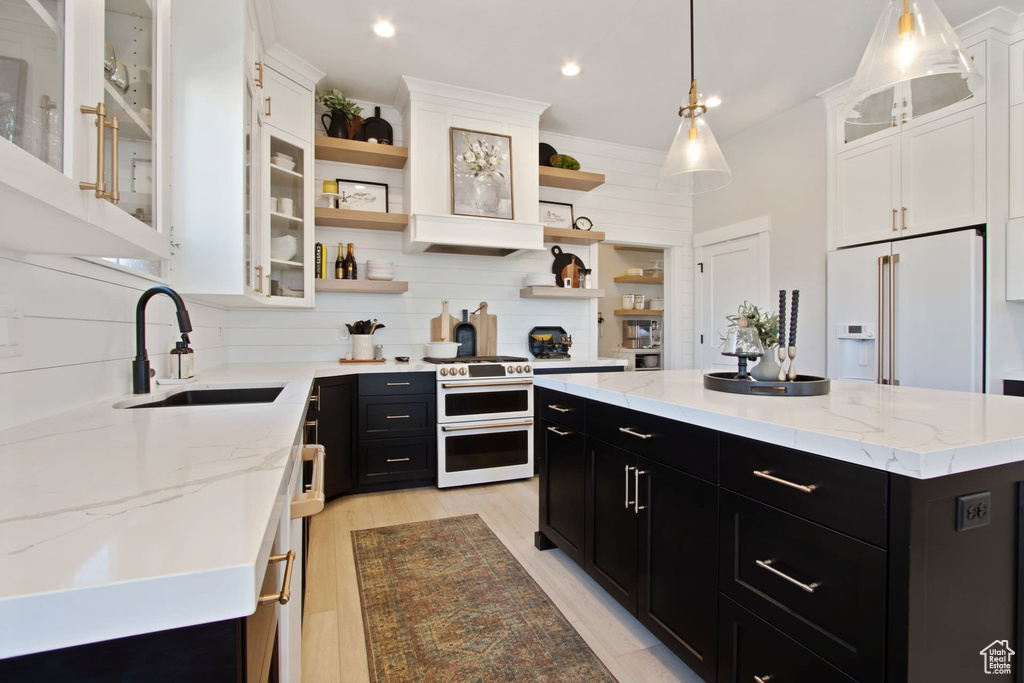 Kitchen with sink, white appliances, tasteful backsplash, hanging light fixtures, and a kitchen island