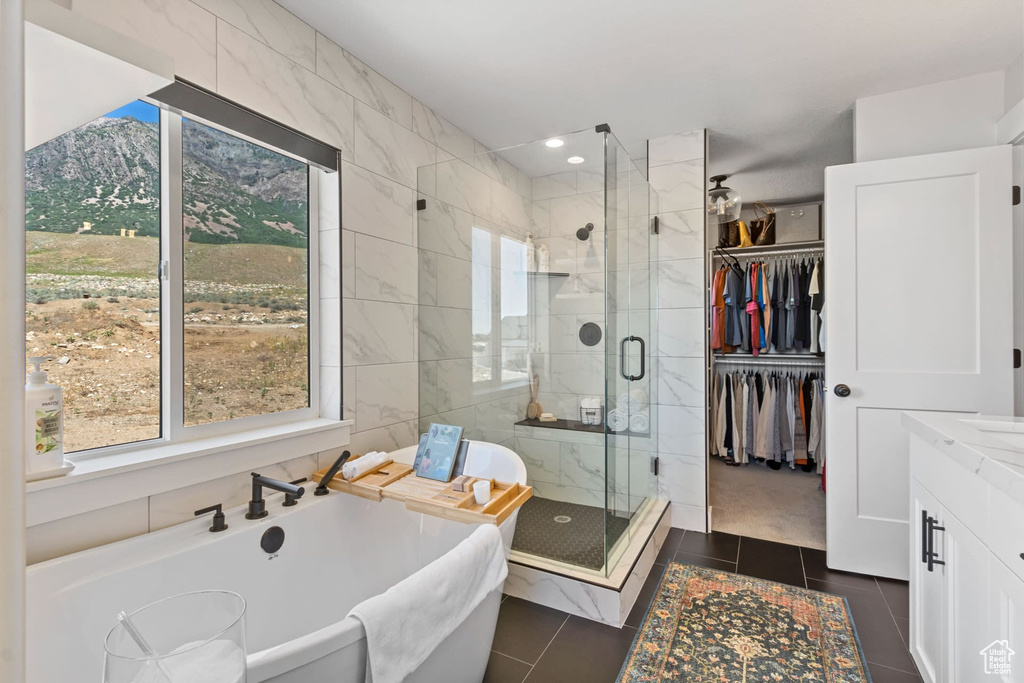 Bathroom featuring vanity, plus walk in shower, tile walls, a mountain view, and tile flooring