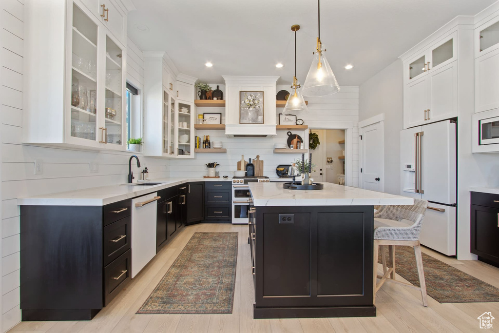 Kitchen featuring a center island, a kitchen breakfast bar, white appliances, pendant lighting, and backsplash