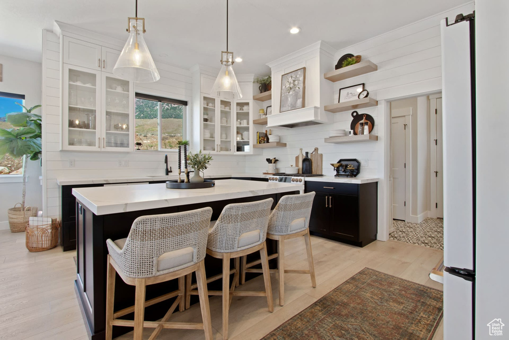Kitchen featuring white cabinets, pendant lighting, a center island, and light hardwood / wood-style floors