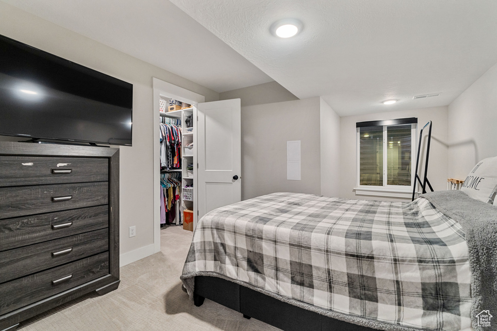 Bedroom featuring light colored carpet, a spacious closet, and a closet