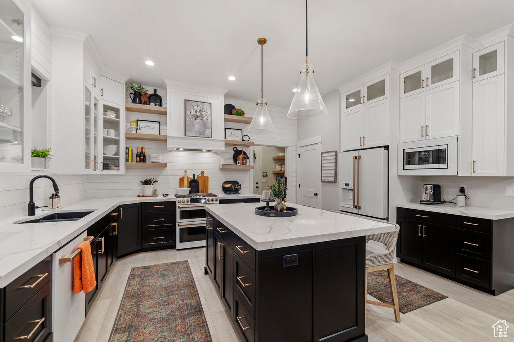 Kitchen with decorative light fixtures, backsplash, a kitchen island, stainless steel appliances, and light stone counters
