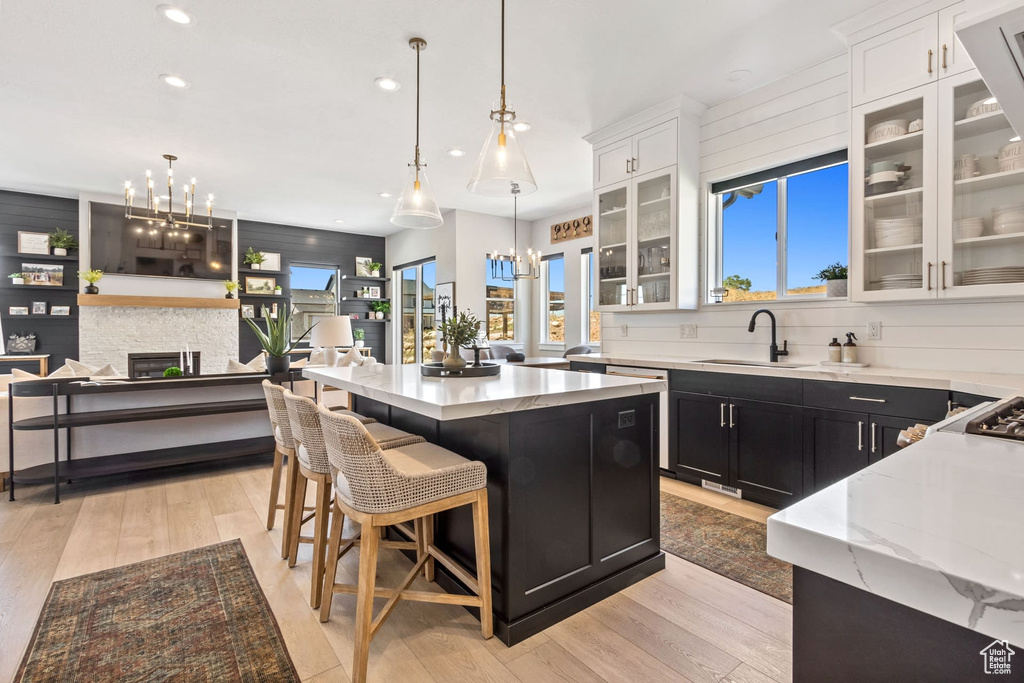 Kitchen featuring white cabinets, an inviting chandelier, a center island, and light hardwood / wood-style flooring