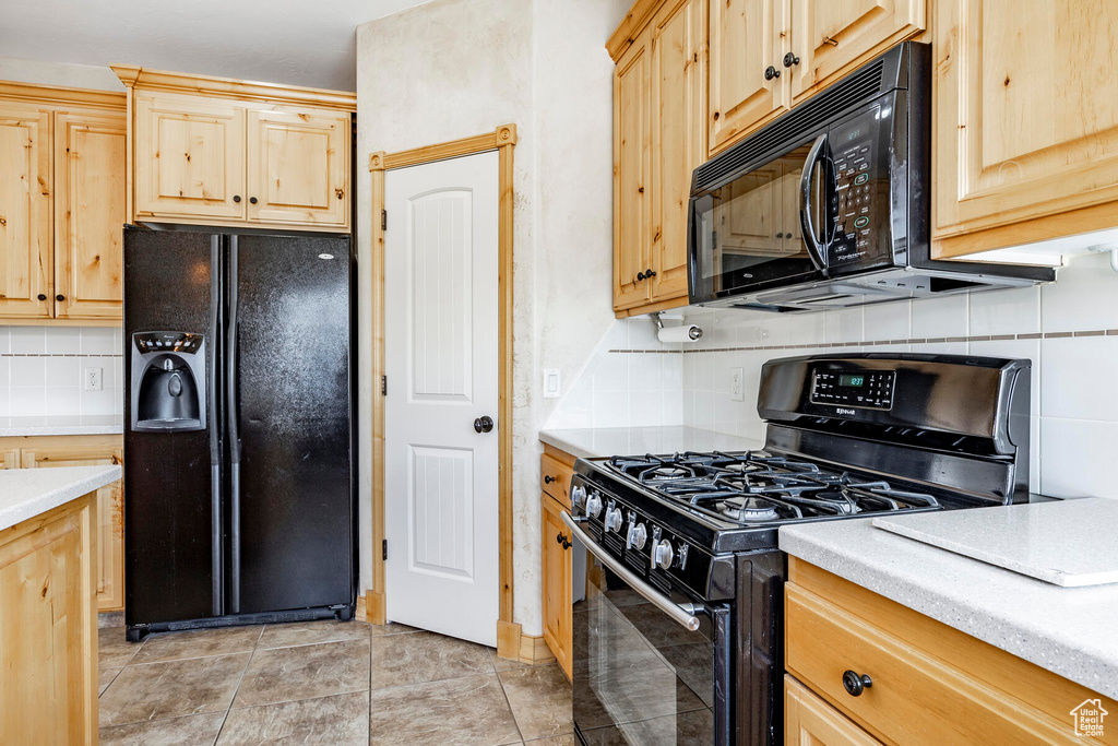 Kitchen with black appliances, tasteful backsplash, light tile flooring, and light brown cabinetry