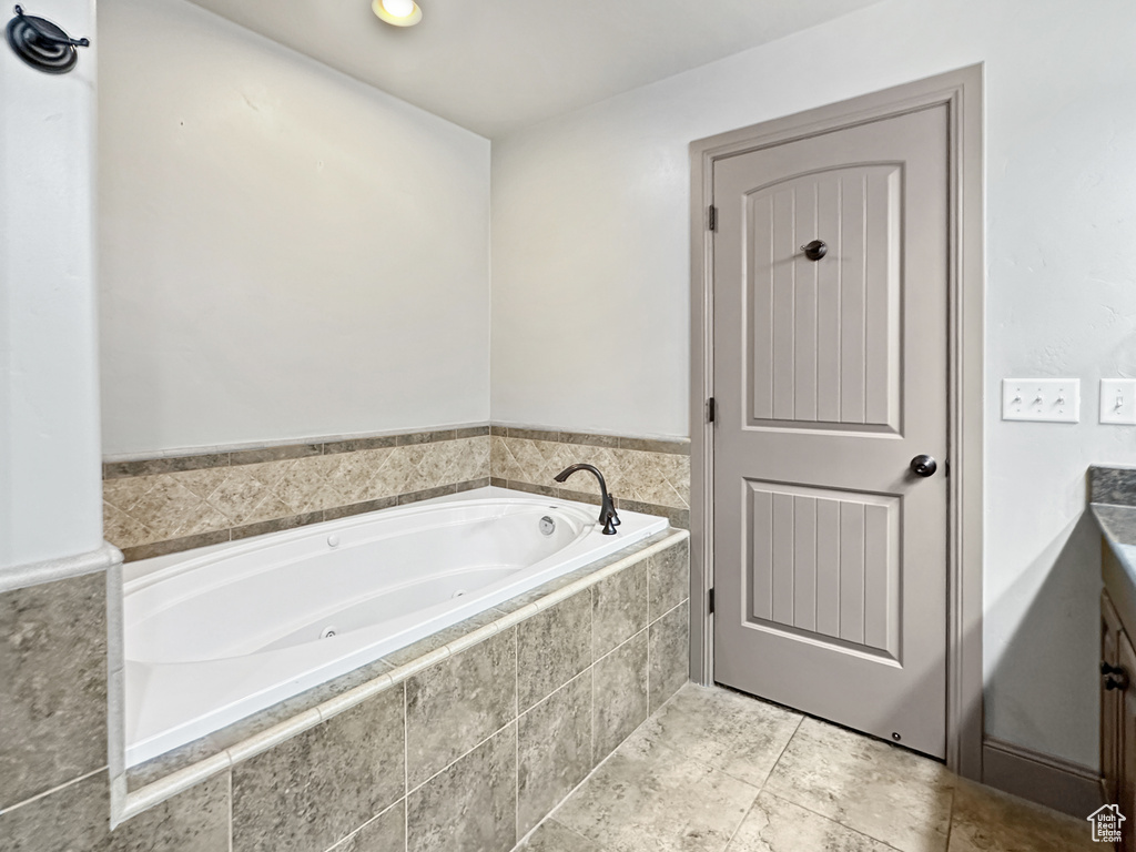 Bathroom with tiled tub and tile flooring