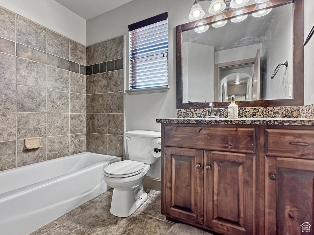 Full bathroom featuring vanity, tiled shower / bath, tile floors, and toilet