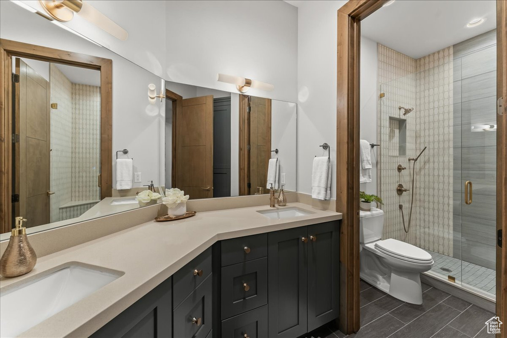 Bathroom featuring walk in shower, toilet, double sink vanity, and tile floors