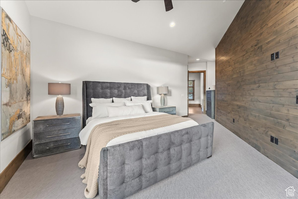 Carpeted bedroom featuring wood walls and ceiling fan