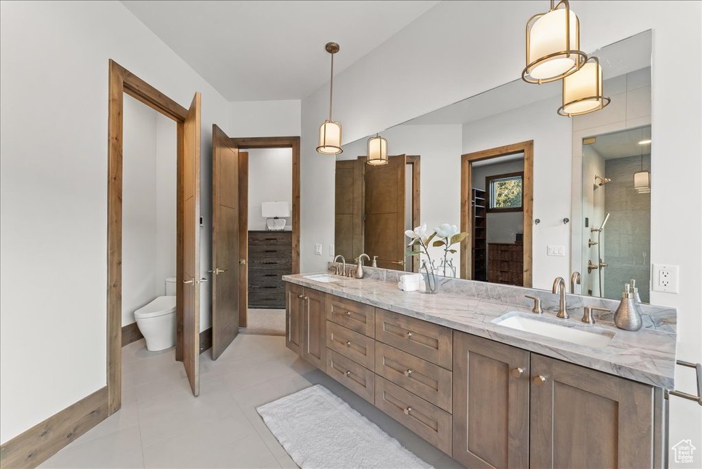 Bathroom with dual vanity, toilet, and tile floors