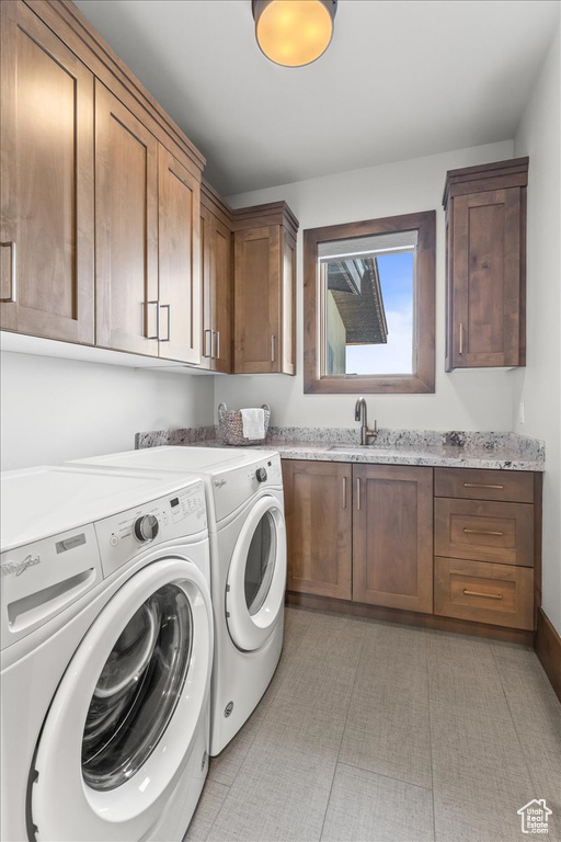 Laundry area with light tile floors, separate washer and dryer, sink, and cabinets