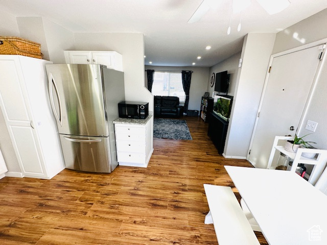 Kitchen featuring stainless steel refrigerator, white cabinetry, hardwood / wood-style flooring, and ceiling fan