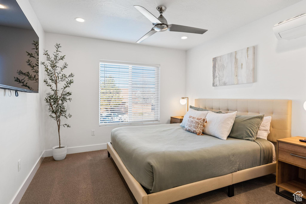 Carpeted bedroom featuring a wall mounted air conditioner and ceiling fan