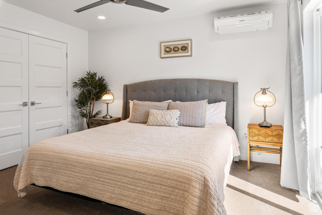 Carpeted bedroom with a wall mounted air conditioner, ceiling fan, and a closet