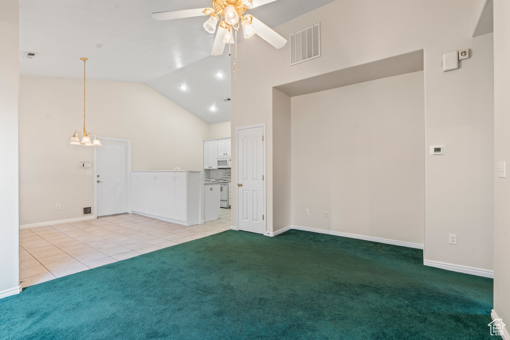 Carpeted spare room with high vaulted ceiling and ceiling fan with notable chandelier